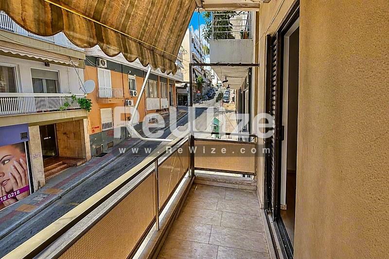 Στενό μπαλκόνι διαμερίσματος στη Χαλκιδική με θέα σε γραφική οδό παραδοσιακής αρχιτεκτονικής.