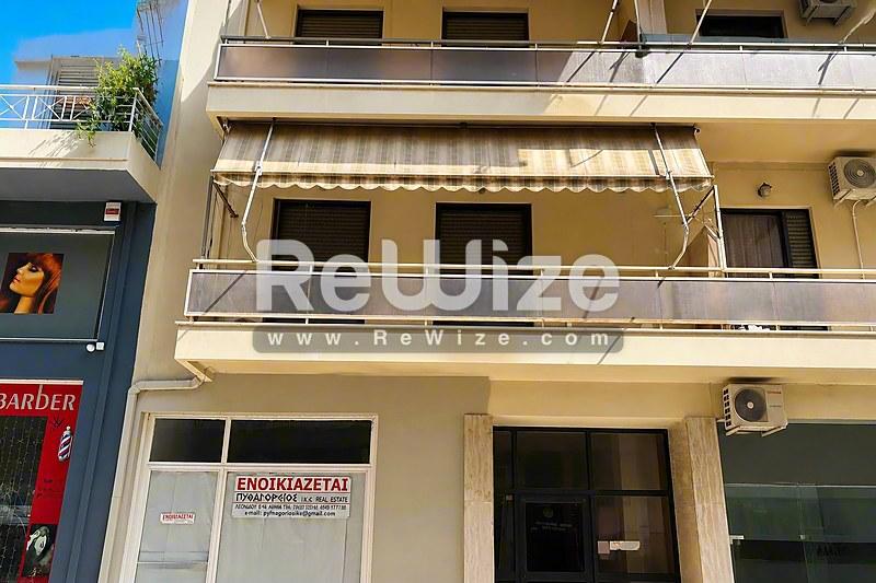 Διαμέρισμα στη Χαλκιδική με κίτρινη-μπεζ πρόσοψη, πολλά μπαλκόνια και εμπορικό χώρο στο ισόγειο.