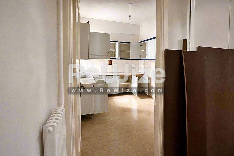 Σύγχρονη κουζίνα σε διαμέρισμα στη Χαλκιδική με ξύλινο δάπεδο και λευκά ντουλάπια.