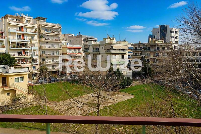 Θέα από το μπαλκόνι διαμερίσματος στη Χαλκιδική με πράσινη αυλή και κατοικίες.