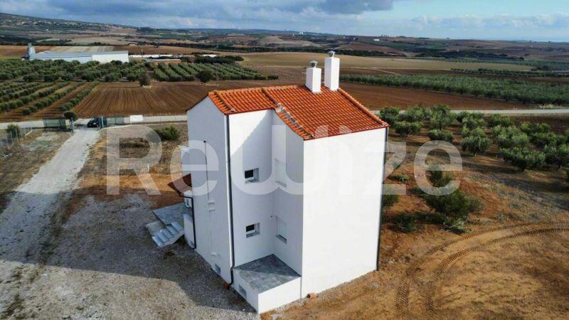 Εναέρια άποψη σύγχρονης μονοκατοικίας με πορτοκαλί κεραμοσκεπή στη Χαλκιδική, περιτριγυρωμένη από αγροτικές εκτάσεις.
