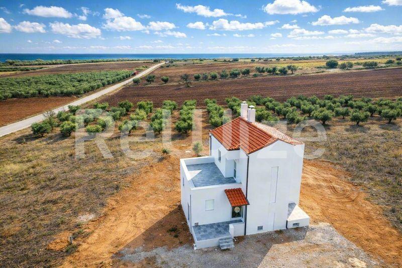 Εναέρια άποψη μιας σύγχρονης μονοκατοικίας με κόκκινη στέγη σε γεωργική γη στη Χαλκιδική.