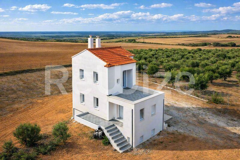 Εναέρια άποψη σύγχρονης μονοκατοικίας με λευκή όψη και κεραμοσκεπή στην Χαλκιδική, περιτριγυρισμένη από γεωργικές εκτάσεις.