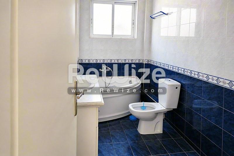 Σύγχρονο μπάνιο με μπανιέρα, λεκάνη και νιπτήρα στο διαμέρισμα της Χαλκιδικής, με μπλε πλακάκια και φυσικό φως.