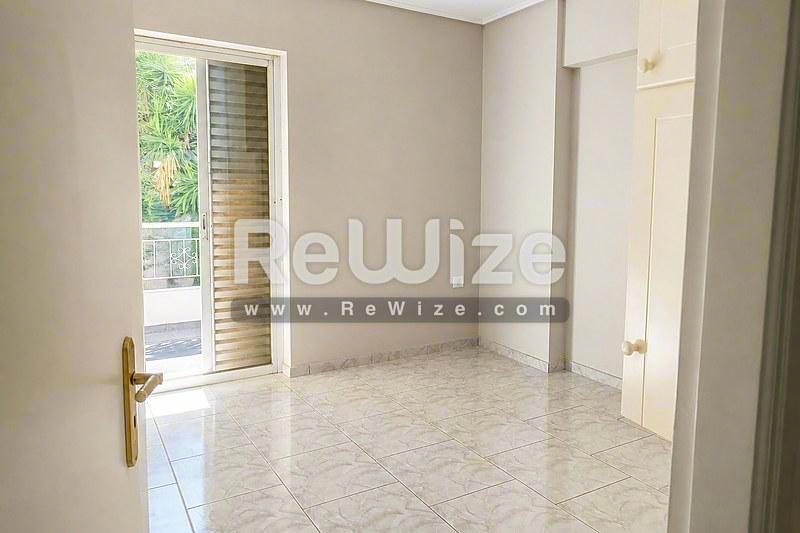 Φωτεινό υπνοδωμάτιο σε διαμέρισμα στη Χαλκιδική με μαρμάρινο δάπεδο και γυάλινη πόρτα προς τον εξωτερικό χώρο.