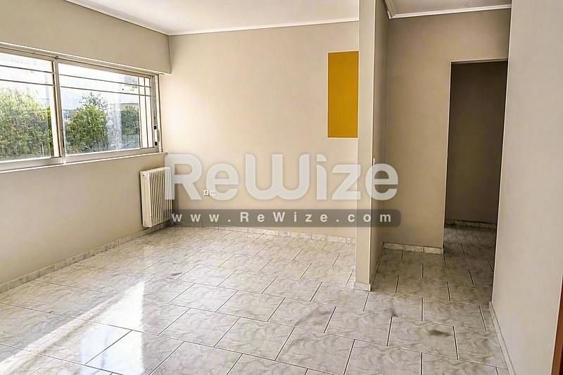 Φωτεινό σαλόνι διαμερίσματος στη Χαλκιδική με πλακόστρωτο δάπεδο, φυσικό φως και πρόσβαση σε άλλους χώρους.