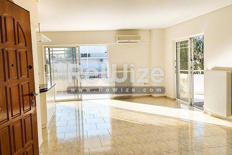 Ευρύχωρο σαλόνι σε διαμέρισμα στη Χαλκιδική με γυαλισμένα πατώματα και φυσικό φως από πολλά μπαλκόνια.