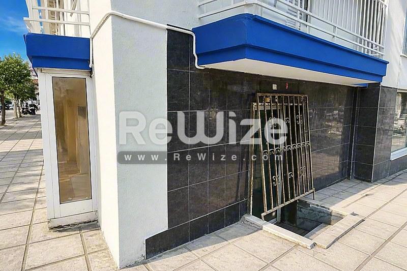 Σύγχρονη προσόψεις καταστήματος με μπλε τέντα στη Χαλκιδική, με σκούρα πλακάκια και γυάλινη πόρτα εισόδου.