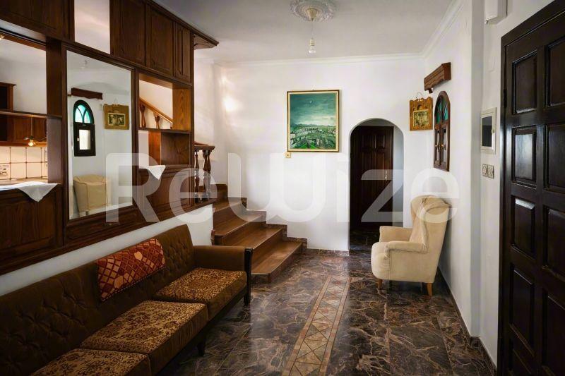 Κομψό σαλόνι μονοκατοικίας στη Χαλκιδική με ξύλινες σκάλες, κλασικά έπιπλα και παραδοσιακές αρχιτεκτονικές λεπτομέρειες.