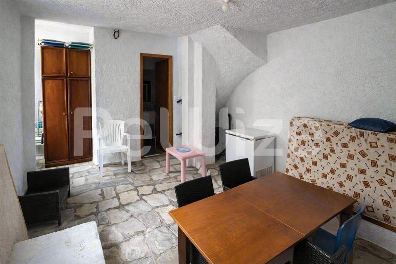 Σαλόνι μεζονέτας στη Χαλκιδική με ξύλινο τραπέζι, καναπέ-κρεβάτι και κλασικά έπιπλα.