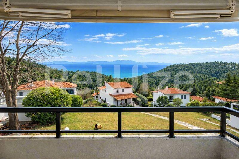 Υπέροχη θέα θάλασσας από μπαλκόνι μεζονέτας στη Χαλκιδική, με τυρκουάζ νερά και πευκοδάσος.