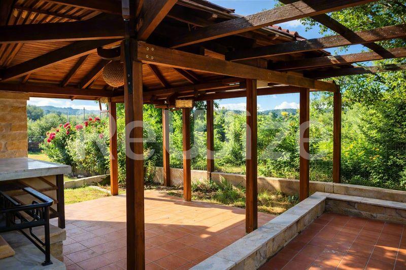 Ξύλινη περγόλα με πέτρινη βάση στη βεράντα μονοκατοικίας στη Χαλκιδική, με θέα στο πράσινο τοπίο.