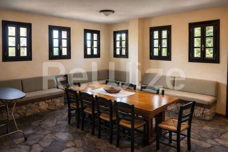 Ευρύχωρη τραπεζαρία σε μονοκατοικία στη Χαλκιδική με ξύλινο τραπέζι, μαύρες καρέκλες και άνετες ζώνες καθίσματος.