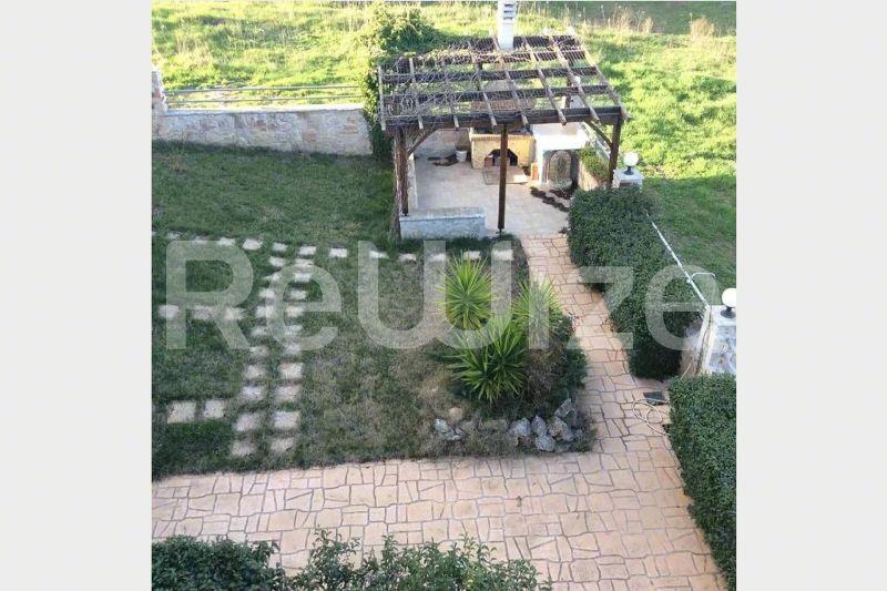 Περγόλα και κήπος μεζονέτας στη Χαλκιδική με πλακόστρωτα μονοπάτια και φυτεύσεις.