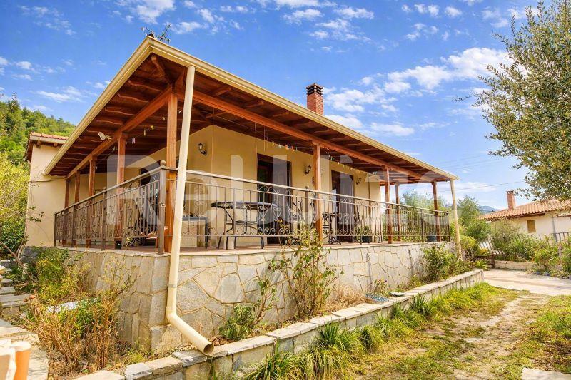 Πρόσοψη μονοκατοικίας στη Χαλκιδική με ξύλινη περγόλα, πέτρινη βάση και περιβάλλουσα φύτευση.