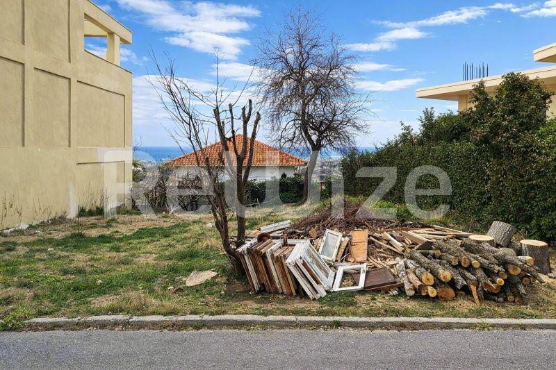 Γήπεδο στην Χαλκιδική με διάσπαρτα δομικά υλικά, γυμνά δέντρα και θέα προς τη θάλασσα.