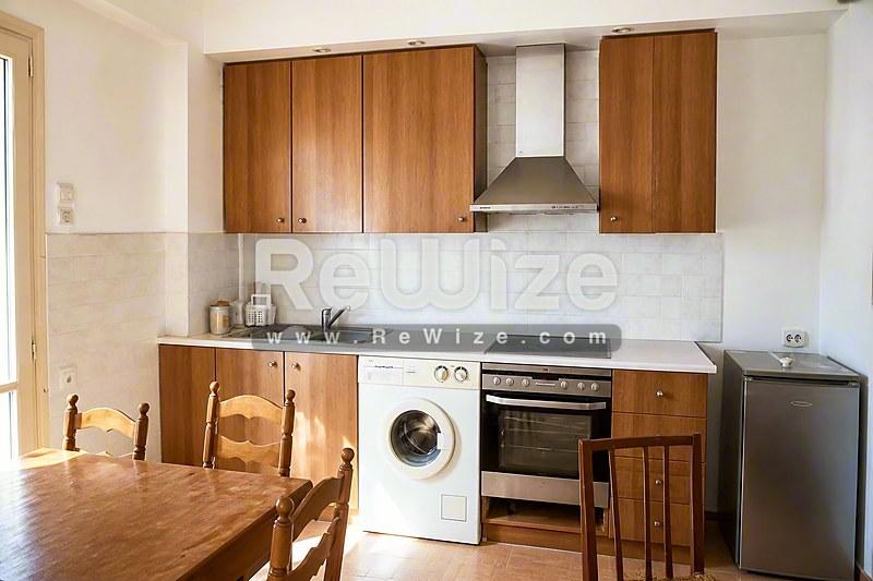 Σύγχρονη κουζίνα διαμερίσματος στη Χαλκιδική με ξύλινα ντουλάπια και σύγχρονες συσκευές.