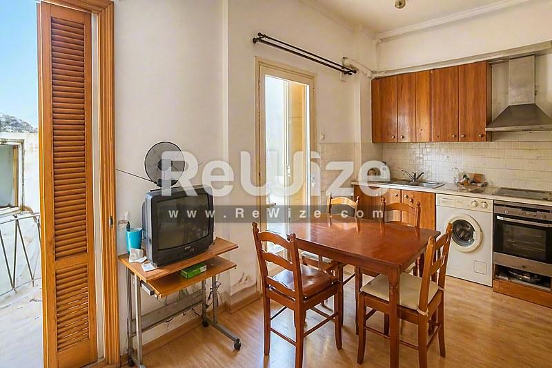 Ανοιχτός χώρος διαβίωσης και κουζίνα διαμερίσματος στη Χαλκιδική με ξύλινο τραπέζι και σύγχρονες συσκευές.