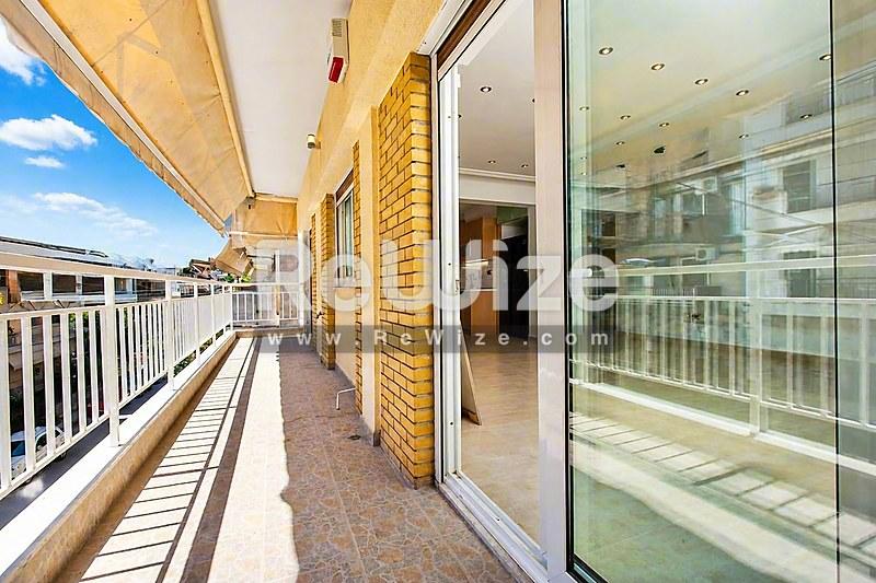 Ευρύχωρη και ηλιόλουστη βεράντα διαμερίσματος στη Χαλκιδική με θέα στη θάλασσα και σύγχρονες γυάλινες κάγγελες.