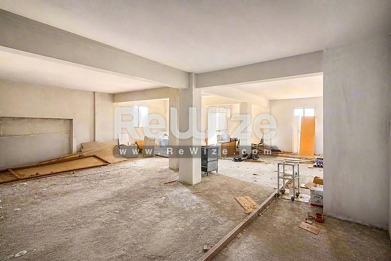 Ευρύχωρο ανοιχτό σχέδιο μονοκατοικίας στη Χαλκιδική, με ημιτελή χώρους διαβίωσης και τσιμεντένια δάπεδα.