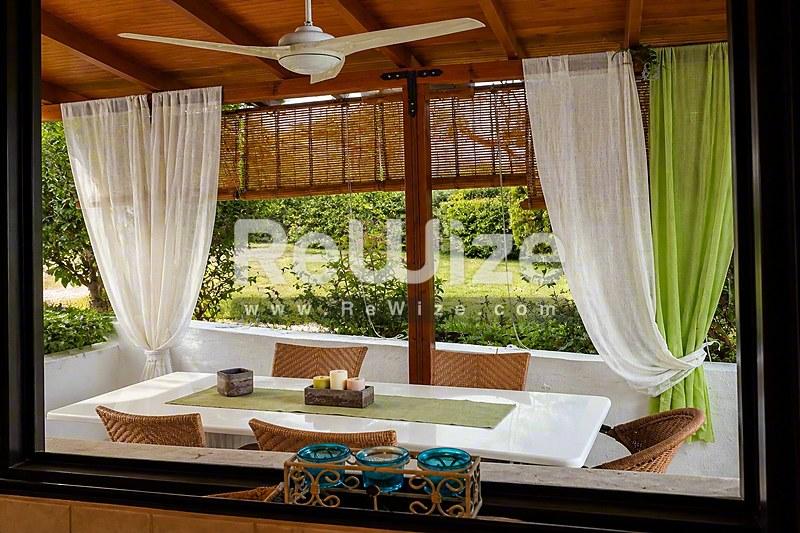 Просторη pergola μεζονέτας στη Χαλκιδική με ξύλινες δοκούς, άνετη συνεδρία και θέα στον κήπο.