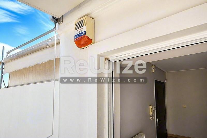 Φωτεινή είσοδος διαμερίσματος στη Χαλκιδική με σύγχρονα λευκά τοιχώματα και φυσικό φως από υάλινη πόρτα.