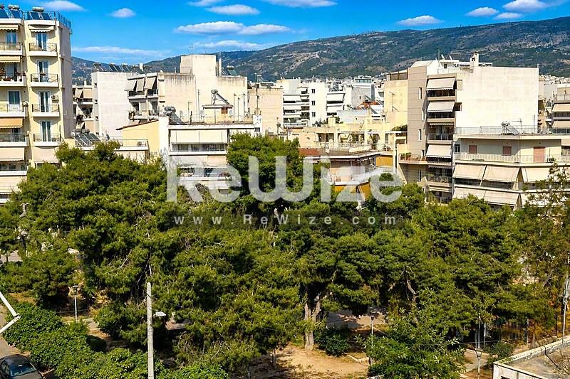 Αστικό περιβάλλον διαμερίσματος στη Χαλκιδική με δέντρα πεύκων και κατοικίες με θέα στα βουνά.