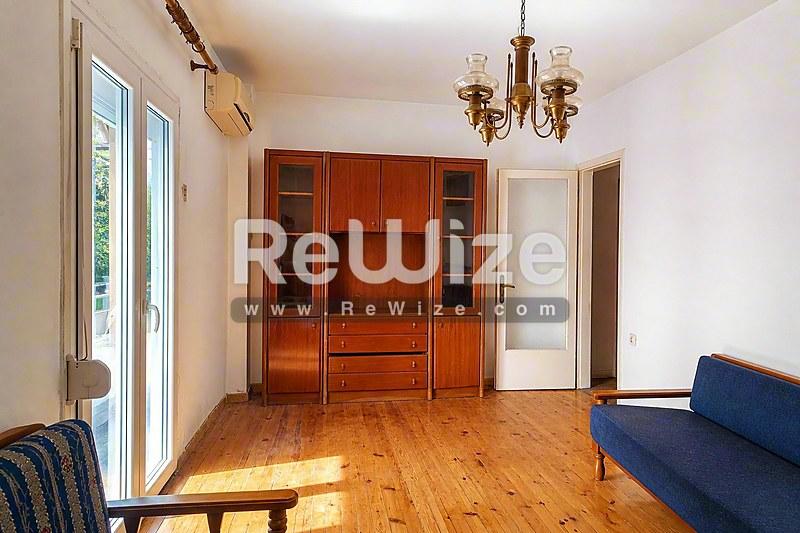 Φωτεινό σαλόνι διαμερίσματος στη Χαλκιδική με ξύλινα πατώματα, ενσωματωμένες ντουλάπες και παραδοσιακή διακόσμηση.
