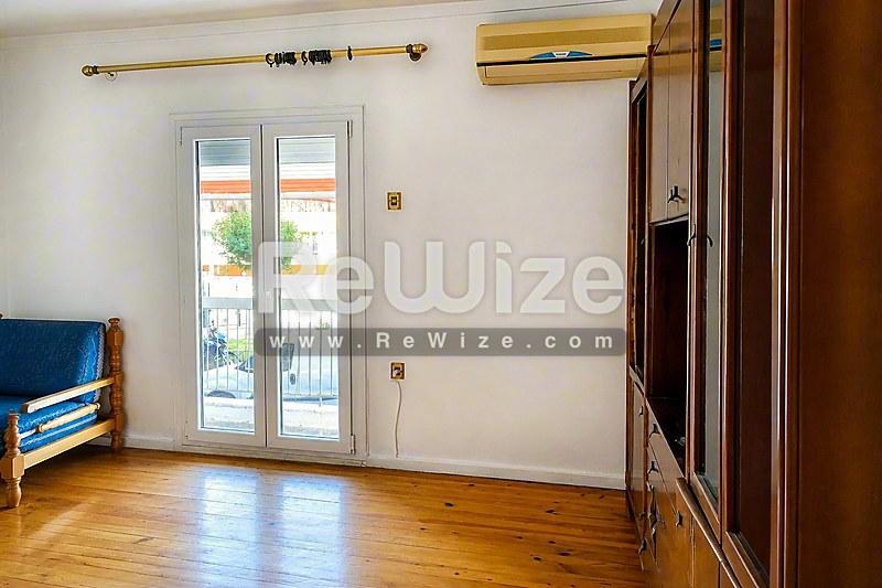 Φωτεινό σαλόνι διαμερίσματος στη Χαλκιδική με ξύλινα πατώματα και γυάλινες πόρτες.