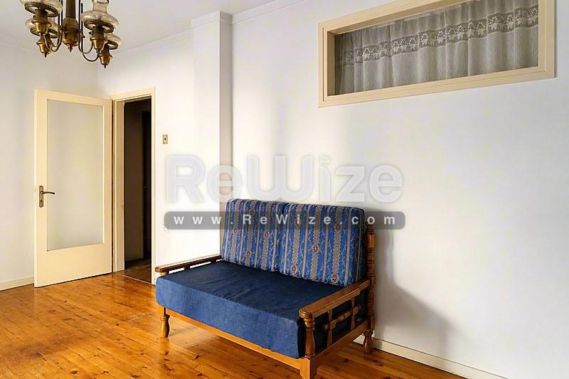 Σαλόνι διαμερίσματος στη Χαλκιδική με μπλε καναπέ, ξύλινο πάτωμα και φυσικό φως.