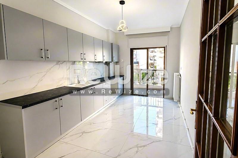 Σύγχρονη κουζίνα διαμερίσματος στη Χαλκιδική με λευκά ντουλάπια και μαρμάρινες επιφάνειες.