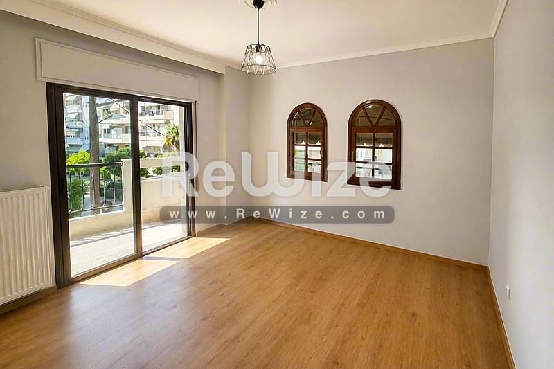 Φωτεινό σαλόνι διαμερίσματος στη Χαλκιδική με ξύλινο δάπεδο, γυάλινες πόρτες και διακοσμητικά καμάρες παράθυρα.