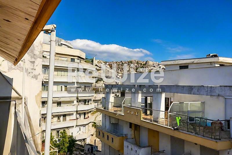 Θέα από το μπαλκόνι ενός διαμερίσματος στη Χαλκιδική με γειτονικά κτίρια και βουνά στο βάθος.