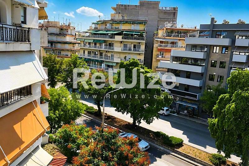 Αστικό περιβάλλον διαμερίσματος στη Χαλκιδική με δενδροστοιχίες, κατοικίες και γαλάζιο ουρανό.