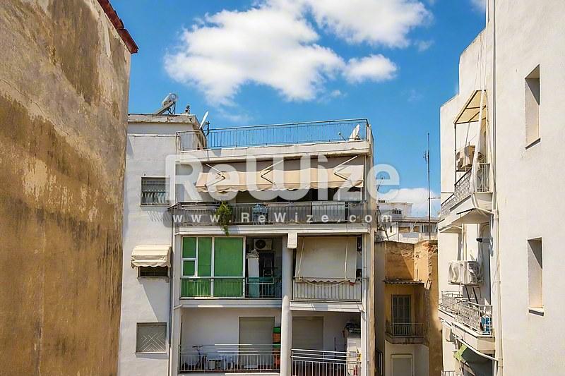 Πρόσοψη διαμερίσματος κατοικίας στη Χαλκιδική με πράσινα παντζούρια και μπαλκόνια κάτω από γαλάζιο ουρανό.