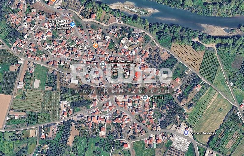 Εναέρια άποψη διαμερίσματος σε κατοικημένη περιοχή της Χαλκιδικής, περιτριγυρωμένο από δέντρα και γεωργικές εκτάσεις.