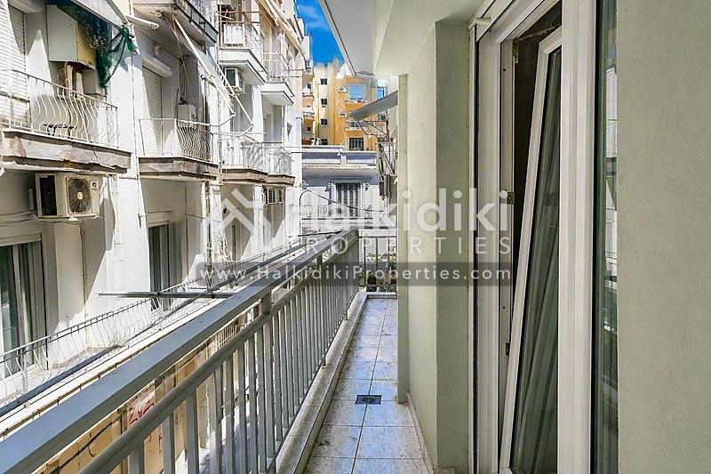 Μπαλκόνι διαμερίσματος στη Χαλκιδική με θέα σε γραφική πεζόδρο με μεσογειακή αρχιτεκτονική.