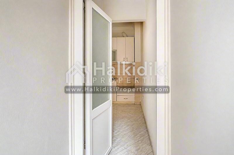 Φωτεινός διάδρομος διαμερίσματος στη Χαλκιδική που οδηγεί σε σύγχρονο μπάνιο με πλακάκια.