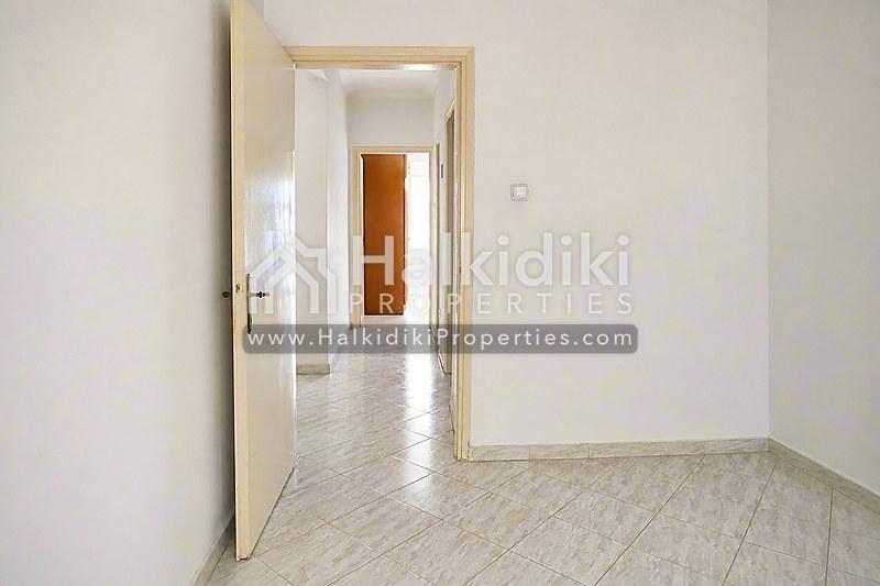 Φωτεινός διάδρομος σύγχρονου διαμερίσματος στη Χαλκιδική με ανοιχτό δάπεδο και καθαρά λευκά τοιχώματα.