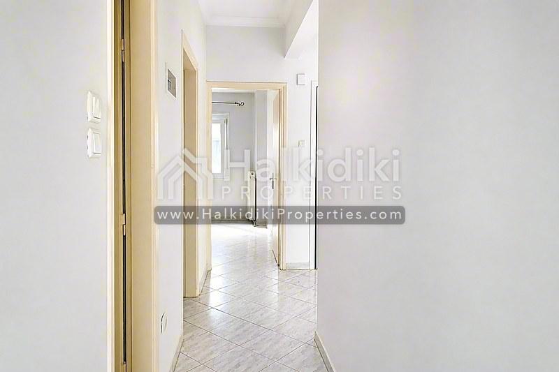 Φωτεινός διάδρομος διαμερίσματος στη Χαλκιδική με ξύλινο δάπεδο σπάρτο και λευκούς τοίχους.