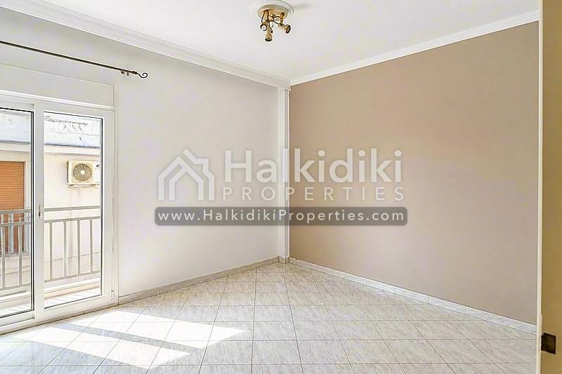 Φωτεινό σαλόνι διαμερίσματος στη Χαλκιδική με πλακόστρωτο δάπεδο και πρόσβαση σε μπαλκόνι.