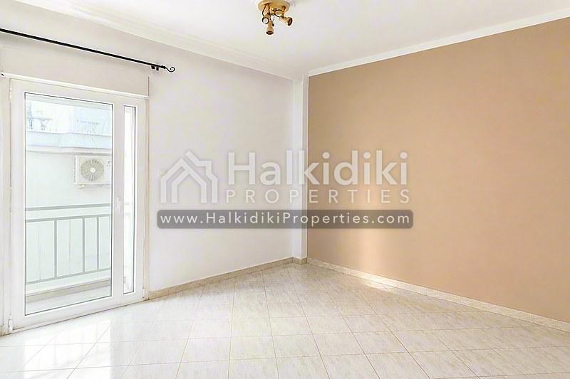 Φωτεινό σαλόνι διαμερίσματος στη Χαλκιδική με μαρμάρινο δάπεδο και θύρα μπαλκονιού.