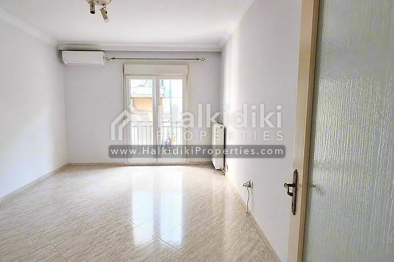 Φωτεινό σαλόνι διαμερίσματος στη Χαλκιδική με γυαλιστερό δάπεδο και γυάλινες πόρτες μπαλκονιού.