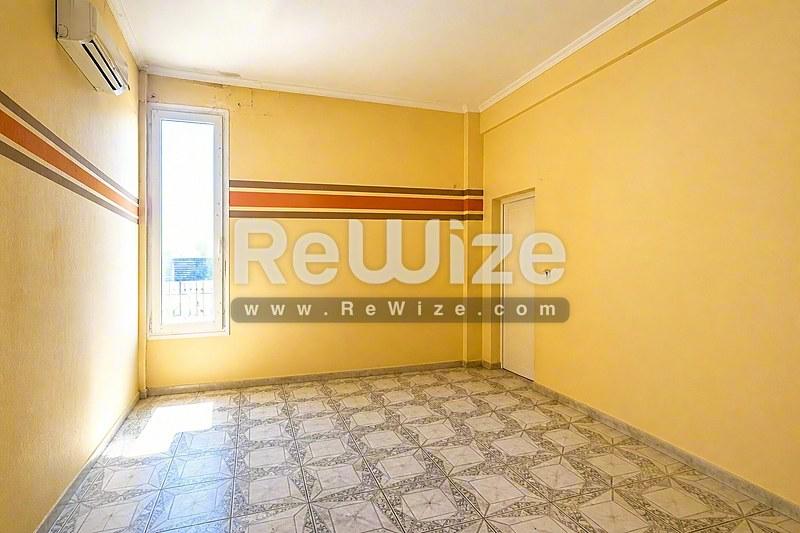 Φωτεινό κίτρινο υπνοδωμάτιο σε βιομηχανικό κτίριο προς πώληση στη Χαλκιδική με μοτίβα δαπέδου.