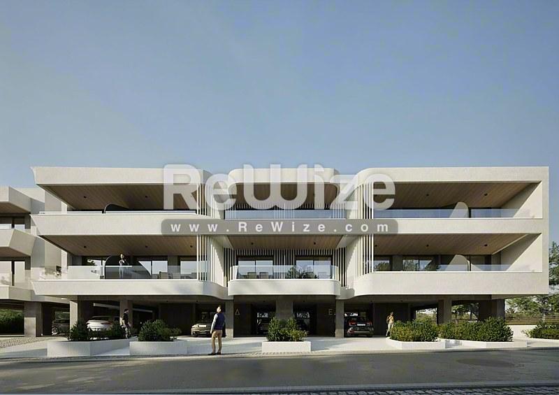 Σύγχρονη πολυκατοικία στη Χαλκιδική με λευκή μπετόν όψη, καμπύλα μπαλκόνια και χώρο στάθμευσης.