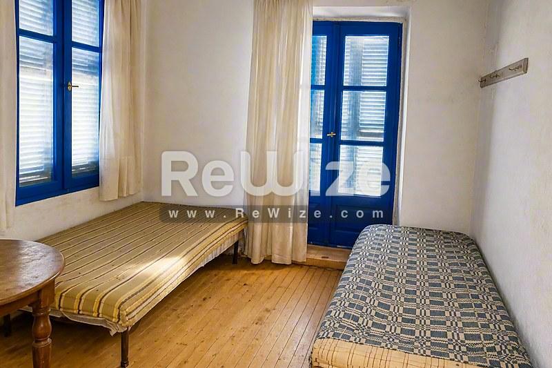 Φωτεινό υπνοδωμάτιο στην ιδιότητα Halkidiki rw-7431 με δύο μονά κρεβάτια, ξύλινο δάπεδο και μπλε παραθυρόφυλλα.
