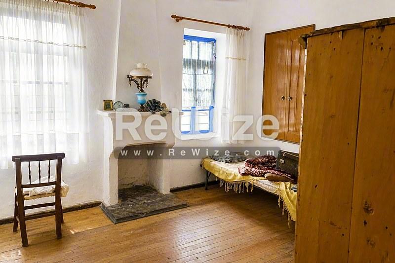 Αγροτικό υπνοδωμάτιο σε παραδοσιακό ακίνητο της Χαλκιδικής με τζάκι, ξύλινα έπιπλα και πήλινα δάπεδα.