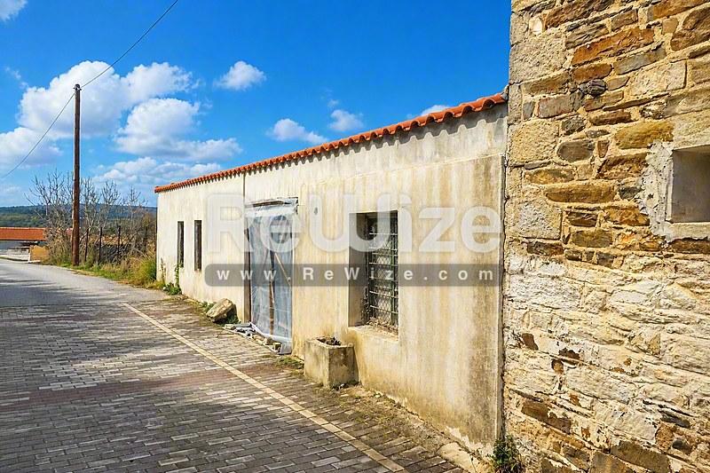 Rustic stone και λευκοσβησμένη πρόσοψη παραδοσιακού κτιρίου στη Χαλκιδική με λεπτομέρειες κεραμικής στέγης.