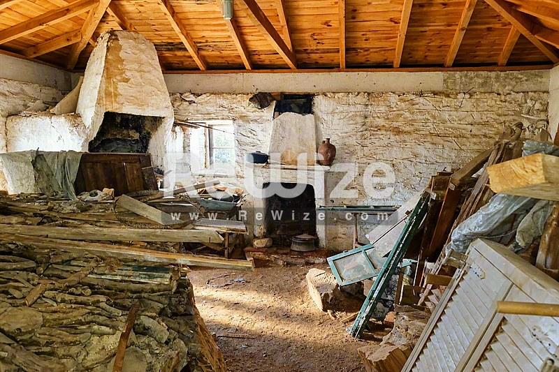 Παραδοσιακός χώρος αποθήκευσης ιδιοκτησίας της Χαλκιδικής με ξύλινες δοκούς και διάσπαρτα αντικείμενα.