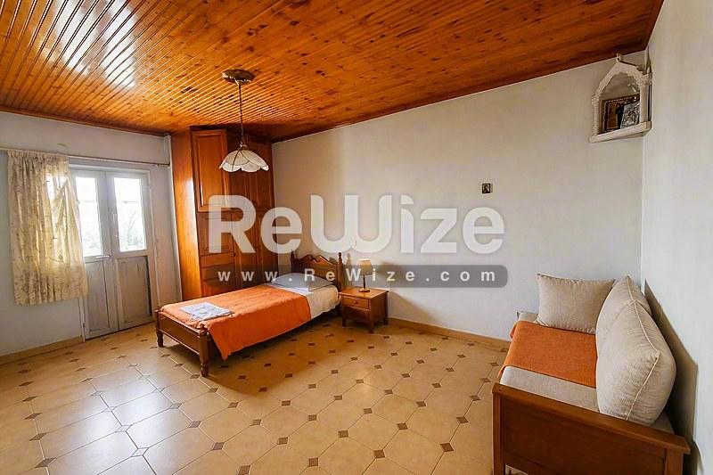 Ευρύχωρο υπνοδωμάτιο στο κτήμα Halkidiki rw-7461 με ξύλινη οροφή, πλακόστρωτο δάπεδο και παραδοσιακά έπιπλα.